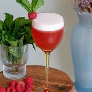 Sustainable cocktail recipes | A red cocktail with foam sitting on a side table