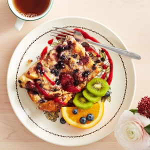 A beautiful slice of toast with fruit and sauce drizzled around the plate