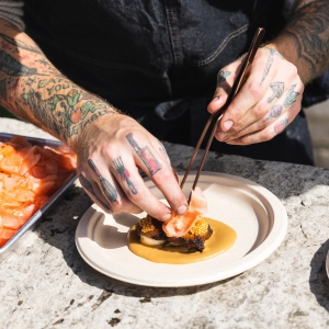 A chef plating an elegant dish with chopsticks