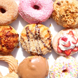A dozen colourful doughnuts with icing and sprinkles