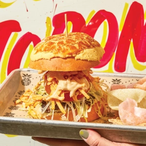 A stacked burger with a vibrant Toronto background