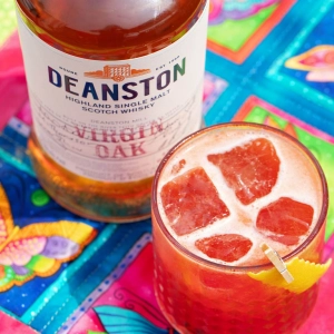 A red cocktail and a bottle of Deanston Virgin Oak