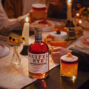 A bottle of Reifel Rye on a dining table with cocktails