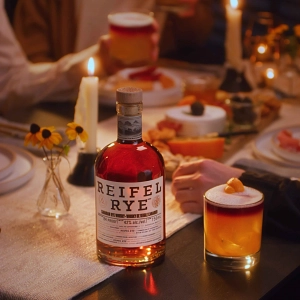 A bottle of Reifel Rye on a dining table with cocktails