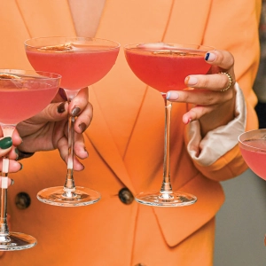 Three people holding red cocktails