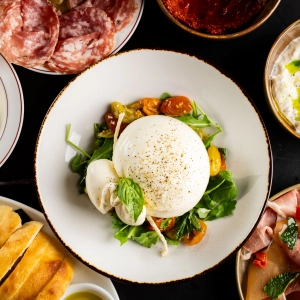 Burrata on a salad surrounded by a spread of other plates