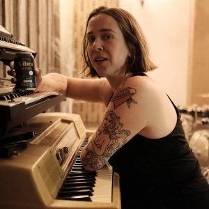 Serena Ryder sitting at a piano with a can of Libra non-alcoholic beer