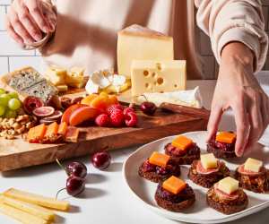 Hands making a spread of European cheeses