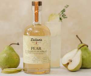 A bottle of Dillon's Pear Gin sits beside pears and a cocktail