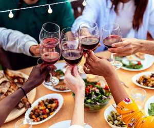 Wine pairings | Friends cheers red wine glasses over a table of food