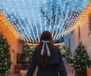 Elora Christmas Market | A woman with a bow wanders under the twinkly lights at the Elora Christmas Market