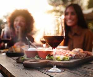Food and wine pairings | A glass of wine on a table with food and a couple in the background