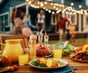 A summer party spread with juice, different plates and guests enjoying themselves in the background