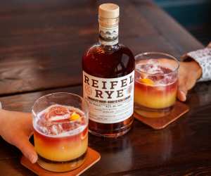 A bottle of Reifel Rye with two sour cocktails