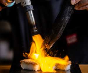 Hello Nori the hand roll bar, Toronto | A hand uses charcoal to blowtorch hand roll sushi